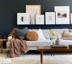 a living room filled with furniture and framed pictures on the wall above it's coffee table