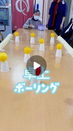 a group of people standing around a wooden table with white and yellow cones on it