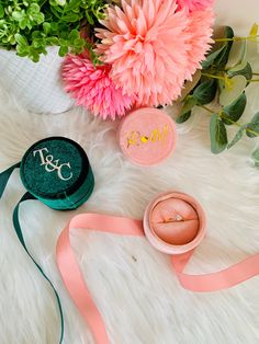 pink flowers, ring box and ribbon laying on white fur with monogrammed initials