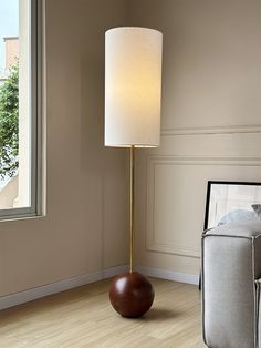 a lamp that is on top of a table next to a couch and chair in front of a window