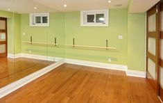 an empty room with green walls and wooden floors, mirrors on the wall and doors