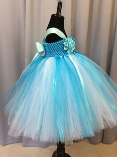 Fuzzy Duckling Design dresses ~ handcrafted for the little princess in your life. Our beautiful flower girl dresses feature a stretchy, crocheted bodice that is fully lined for both comfort and modesty. These extra full skirts sparkle and shine with four layers of high quality tulle in matte, shimmer, and glitter finishes. Satin ribbons and flowers are added to make each dress something special. To determine the length of dress to order: measure from where the top edge of the bodice will start ( Fitted Blue Tutu Dress For Wedding, Blue Tulle Tutu Dress For Pageant, Whimsical Tulle Tutu Dress For Wedding, Blue Princess Dress With Tulle Skirt For Wedding, Whimsical Wedding Tutu Dress With Tulle Skirt, Whimsical Blue Fitted Tutu Dress, Blue Whimsical Fitted Tutu Dress, Blue Fitted Whimsical Tutu Dress, Princess Style Light Blue Tulle Tutu Dress