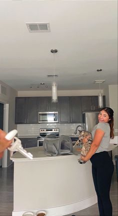 a woman standing in front of a kitchen counter holding a pair of scissors