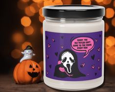 a halloween candle with a ghost on it next to a jack - o'- lantern