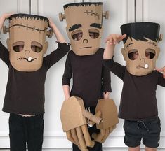 three children wearing paper mache costumes with their hands in the air and one holding his head