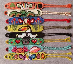 five colorful beaded bracelets are lined up on a gray surface, each with different designs and colors