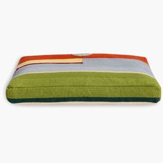 a green and blue striped dog bed on a white background with an orange, yellow, red, and grey stripe