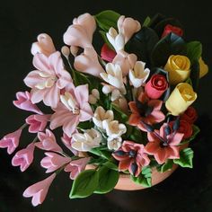 a vase filled with lots of colorful flowers on top of a black table next to a wall