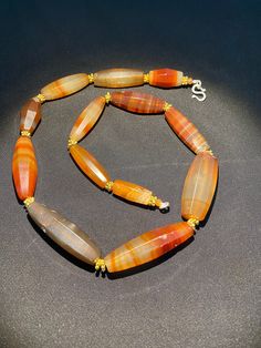 an orange and brown beaded necklace on a black surface