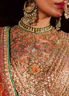 Pakistani Bridal Dress in Pishwas Frock Sharara Style is a breathtaking attire that has the perfect balance of traditional and elegant look. This stunning Pakistani Wedding Dress is adorned with hand-crafted details of adda work and shimmering ornaments, making this attire an epitome of beauty and grace. Pakistani Bridal Pishwas: Pakistani Bridal Pishwas in an alluring rose gold color is beautifully embellished with the intricate embroidery and ornaments. Shimmering silver gold work, tilla, zardosi, motifs, sequins, crystals, and pearls give a glamorous touch to this perfectly stitched Pakistani Wedding Dress. The fabric of this Pishwas Dress is net. Bridal Sharara: The embellished Pishwas Frock is paired with Sharara, creating a lavish Pakistani Bridal Dress. The Bridal Sharara comes in p Bollywood Hand Embellished Dupatta For Traditional Ceremonies, Festive Hand Embellished Lehenga For Traditional Ceremonies, Traditional Hand Embellished Anarkali Set For Navratri, Anarkali Traditional Wear For Navratri, Hand Embellished, Hand Embellished Anarkali For Navratri, Navratri Hand Embellished Anarkali Traditional Wear, Hand Embellished Dresses For Navratri Festival, Traditional Hand Embellished Organza Lehenga, Hand Embellished Organza Anarkali Set For Festivals