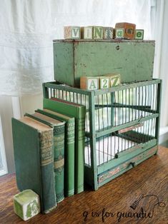 several books are stacked on top of each other in an old green box with letters