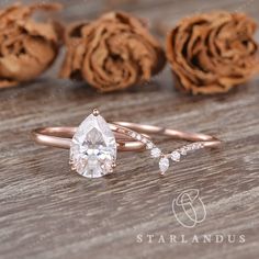 an engagement ring with a pear shaped diamond on it and rose petals in the background