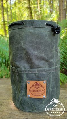 the back side of a green canvas bag with brown leather handles and an emblem on it