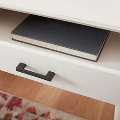 a white desk with a black book on it