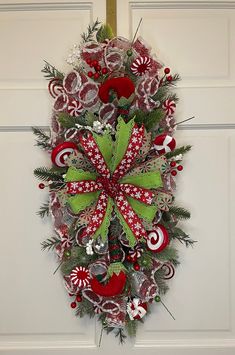 a christmas wreath with candy canes and bows hanging on a door handle, decorated with red and green decorations