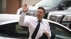 a man in white shirt and black tie waving