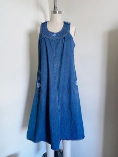 "70's embroidered denim dress. Features a flared style, side pockets, embroidery, medium weight denim, midi length, non functioning shoulder buttons, back button closure, and a loose fit.  Label: None Size Marked: None Estimated Size: Loose Medium Material: 100% Cotton   Color: A bit darker than photographed  Condition: Excellent, some areas of wear Measurements:     Chest: 19 1/2\"     Waist: 21\"     Hips: 25\"      Length: 43 1/2\" Measured flat, Please double width measurements for total. Pl Medium Wash Cotton A-line Denim Dress, Medium Wash Cotton A-line Dress, Medium Wash A-line Cotton Dress, Bohemian Denim Dresses With Pockets, Medium Wash Cotton Mid-length Dress, Retro Sleeveless Denim Dress For Spring, Vintage Denim Blue Knee-length Dress, Vintage Knee-length Denim Blue Dress, Retro Cotton Denim Dress With Pockets