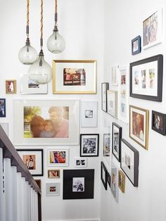 a staircase with many pictures on the wall and framed photos hanging up against the wall