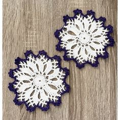 two crocheted doily on wooden surface with white and purple flowers in the center