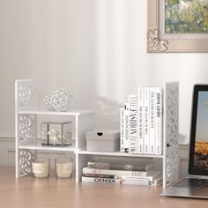 an open laptop computer sitting on top of a wooden desk next to books and candles