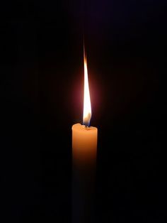 a lit candle in the dark on a black background