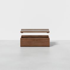 a wooden box sitting on top of a white floor next to a wall in the background