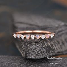 a pink opal and diamond ring sitting on top of a piece of rock next to some rocks