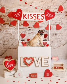 a small pug dog sitting on top of a love sign with hearts around it