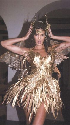 a woman in a costume with feathers on her head and hands behind her head, posing for the camera