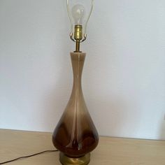 a brown vase with a light on top of it sitting on a table next to a white wall