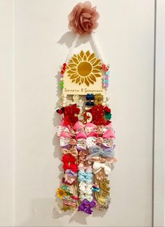 a wall hanging made out of different types of hair clips and bows with a sunflower on top