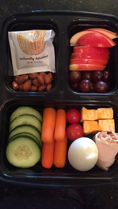 two black trays filled with different types of fruits and veggies on top of each other