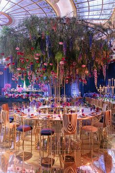 an elaborately decorated banquet hall with tables, chairs and hanging flowers on the ceiling