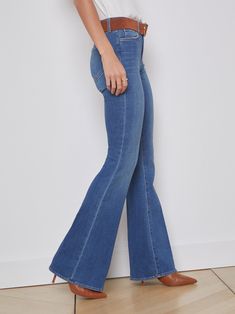 A vintage-inspired bell-bottom jean in medium blue with classic fading and whiskering. Premium stretch denim in a light blue hue has a contoured waistband that fits securely around the natural waist as it smooths and slims, while the premium stretch denim hugs hip, thigh, and fitted through the knee before releasing into a sleek straight leg which can be altered up to 4" without drastically changing the shape. | L'AGENCE Bell Jean In Authentique Fitted Flare Jeans In Medium Wash, Classic Blue Flare Full-length Jeans, Classic Blue Full Length Flare Jeans, Medium Wash Fitted Mid-rise Flares, Fitted Full-length Medium Wash Flares, Fitted Blue Flare Jeans, Blue Fitted Flare Jeans, Classic Stretch Medium Wash Flare Jeans, Medium Wash Stretch Flare Jeans