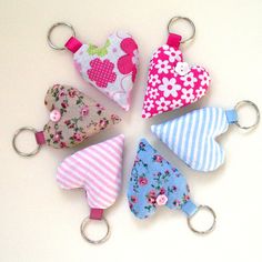 four heart shaped keychains sitting on top of each other in front of a white background