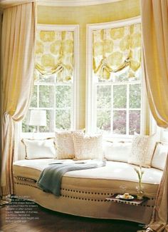 a white couch sitting in front of a window with curtains on the windowsills