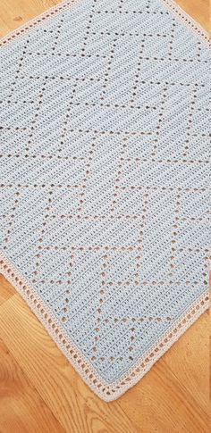 a blue crocheted rug on the floor with wood floors in the background and a wooden floor