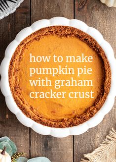 a pumpkin pie with graham cracker crust in a white dish on a wooden table