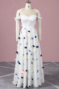 a white dress with blue and yellow butterflies on it, sitting on a mannequin