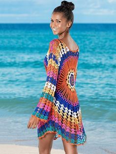 a woman standing on top of a beach next to the ocean wearing a colorful dress