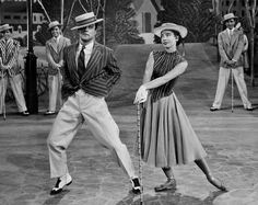 the man and woman are dancing together in front of other men on stage wearing hats