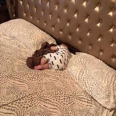 a small child sleeping on top of a bed in a room with a headboard