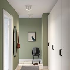 an empty hallway with green walls and white trimmings, including a black chair