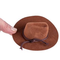 Mini Brown Flocked Cowboy Hat. This Small Brown Flocked Cowboy Hat is a great accessory for displaying with various western decor and fashioning with small dolls and stuffed animals.    The cowboy hat is covered in brown velveteen coating and its crown is detailed with rope trim. This small cowboy hat makes for a darling placeholder or favor for western-themed, events, barbecues, and weddings.    Made of felt, plastic, and polyester. Brown Cap Felt Hat For Rodeo, Brown Felt Cap For Rodeo, Western Style Brown Cap Costume Hat, Brown Cap For Western-themed Events, Brown Flat Brim Costume Hat For Western-themed Events, Western Style Brown Wide Brim Mini Hat, Brown Wide Brim Western Mini Hat, Western Style Wide Brim Mini Hat In Brown, Brown Mini Hat With Short Brim For Rodeo