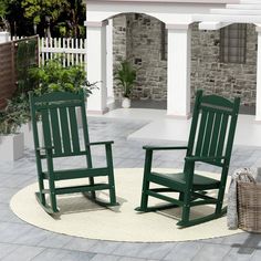 two black rocking chairs sitting on top of a white rug in front of a house