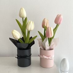 two vases with tulips in them sitting on a table next to each other