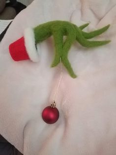 an elf's head hanging from a christmas ornament on a white blanket