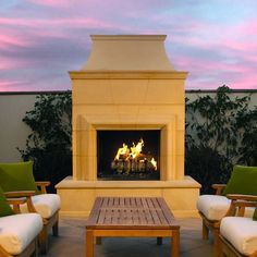 a fire place sitting on top of a patio next to two chairs and a table