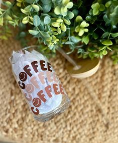 a glass with coffee on it sitting next to a potted plant