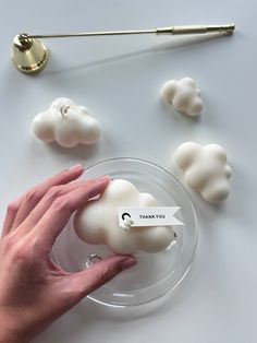 a hand holding a plastic object in front of some fake clouds on a plate with a name tag